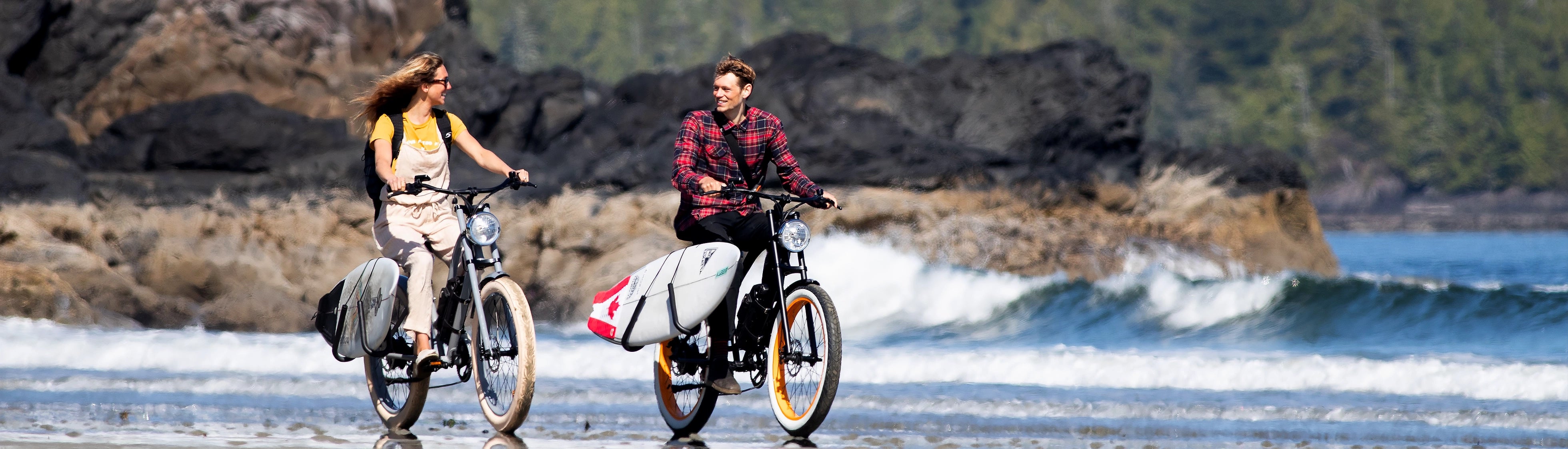 Two individuals riding Michael Blast eBikes on beach 